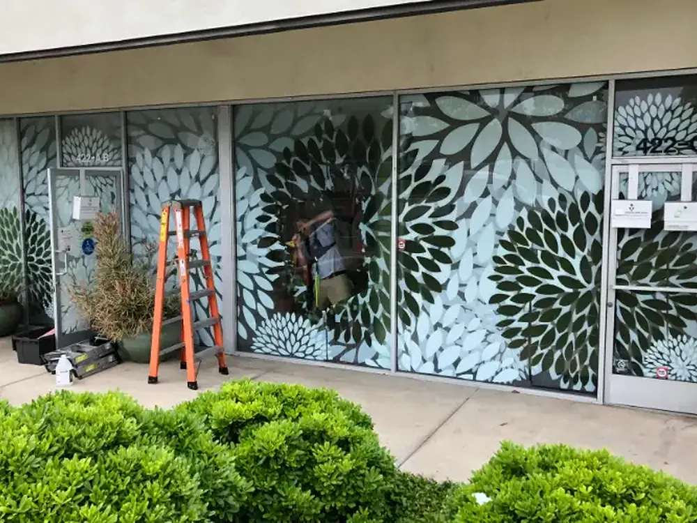 A storefront glazed with a decorative dahlia-pattern privacy film across every pane.
